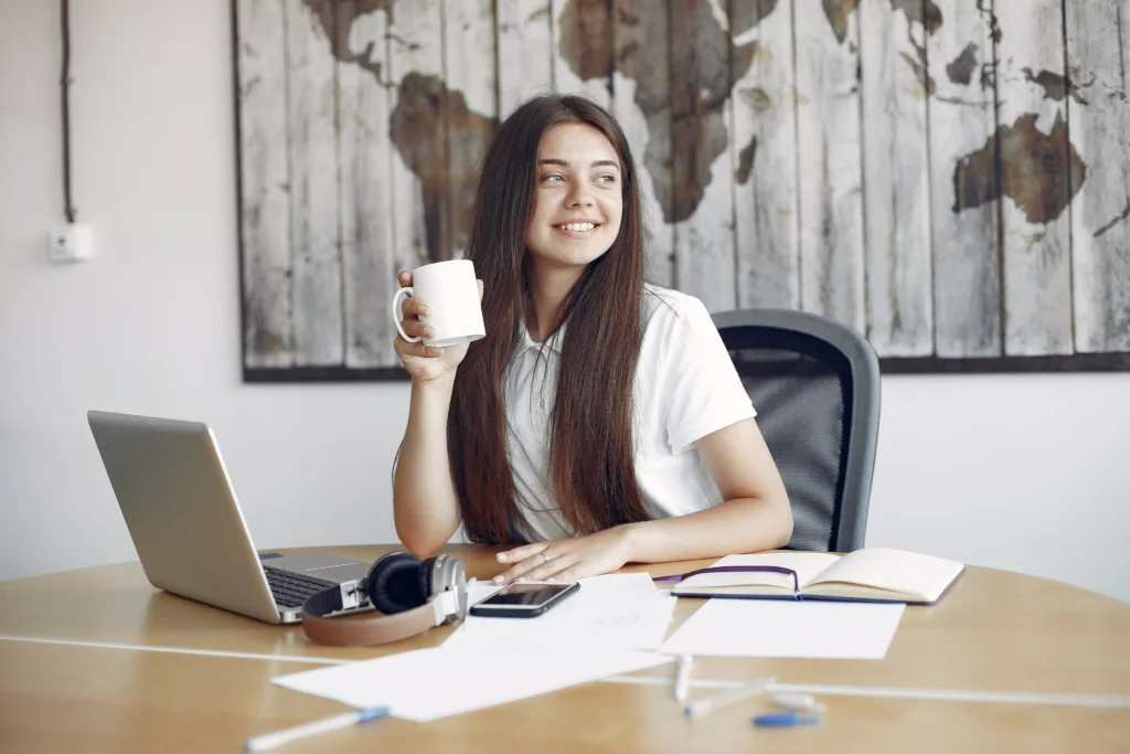 En kvinde på arbejde der smiler med sin kaffe